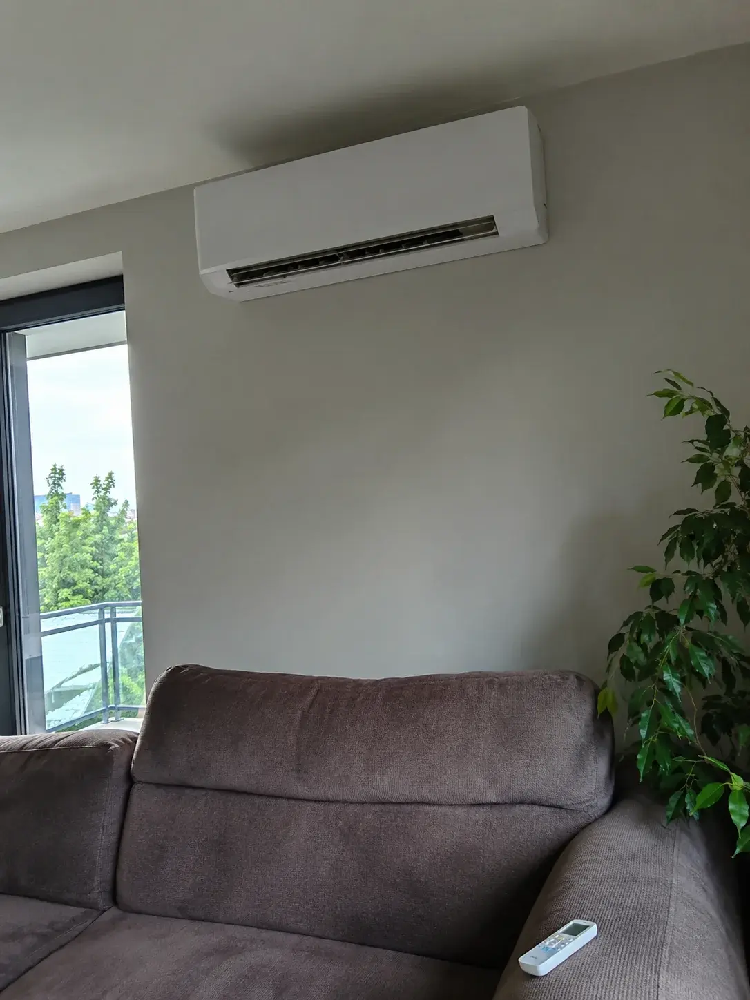 Inverter klima na zidu moderne dnevne sobe sa daljinskim na kauču
